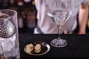 vodka martini isolated on a black background with an olive splashing and air bubbles