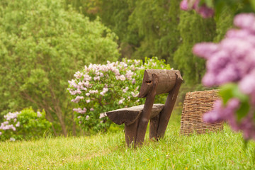 Obraz na płótnie Canvas Wooden bench in a wildflower green garden with trees, in spring or summer