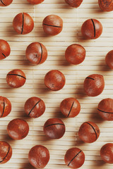 Flat composition with Australian macadamia nuts on bamboo light background. Patterns, repetitions