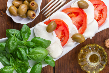 Swieza mozzarella z plastrarmi pomidora i listkami bazyli. Rustykalna kuchnia. Wegetarianskie danie. Vege salatka. © ff25