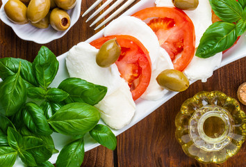 Swieza mozzarella z plastrarmi pomidora i listkami bazyli. Rustykalna kuchnia. Wegetarianskie danie. Vege salatka. © ff25