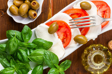 Swieza mozzarella z plastrarmi pomidora i listkami bazyli. Rustykalna kuchnia. Wegetarianskie danie. Vege salatka. © ff25