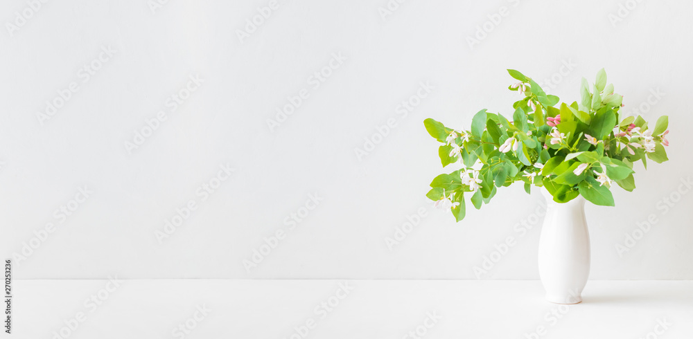 Wall mural home interior with decor elements. branches with green leaves in a vase on a white table