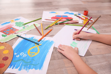 Little girl drawing with color pencils on floor