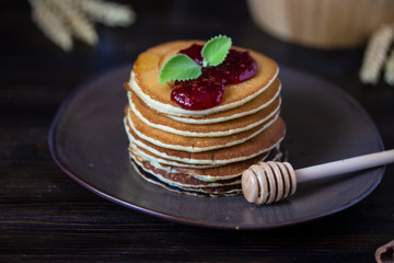 delicious pancakes with jam and mint on a dark wooden table