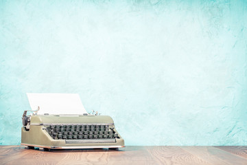 Retro classic typewriter from circa 50s with sheet of paper on wooden desk front textured...