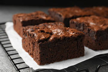 Fototapeta na wymiar Cooling rack with fresh brownies on grey table, closeup. Delicious chocolate pie