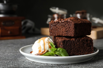 Plate with fresh brownies and ice-cream on table, space for text. Delicious chocolate pie