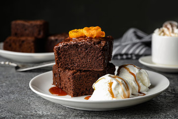Plate with fresh brownies and ice-cream on table. Delicious chocolate pie