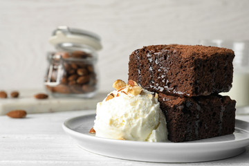 Plate with fresh brownies and ice-cream on table, space for text. Delicious chocolate pie