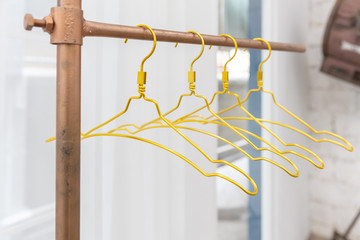 close-up of golden metal clothes hanger on copper clothesline with white curtain background.