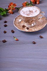 Freshly brewed coffee with milky foam topped with cinnamon in a cup against the gray wooden background