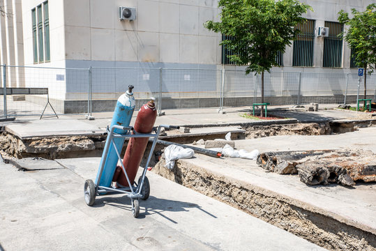 Welding equipment, Two acetylene and oxygen gas tanks for welding with pressure gauge and hose on the trolley in street construction site of district heating pipeline system