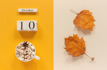 Autumn composition. Wooden calendar October 10, cup of cocoa with marshmallows and yellow autumn leaves on yellow beige background. Top view Flat lay Mockup Concept Hello September