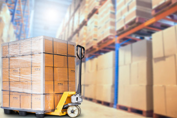 hand pallet truck with the product boxes stacked on pallet. tall shelves storage in warehouse...