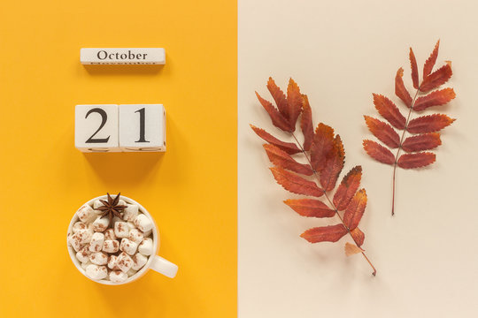 Autumn composition. Wooden calendar October 21, cup of cocoa with marshmallows and red yellow autumn leaves on yellow beige background. Top view Flat lay Mockup Concept Hello September