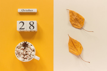 Autumn composition. Wooden calendar October 28, cup of cocoa with marshmallows and yellow autumn leaves on yellow beige background. Top view Flat lay Mockup Concept Hello September