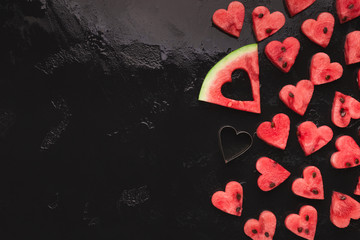 Heart shaped watermelon pieces, big slice and cutter on black