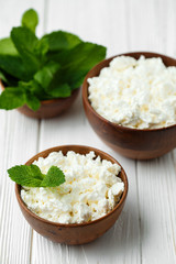 fresh homemade cottage cheese in a wood bowl with mint leaves, on white background. top view
