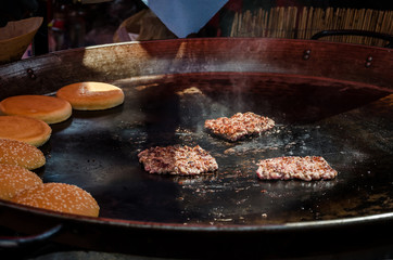 street food, hamburgers and meat patties in a large frying pan