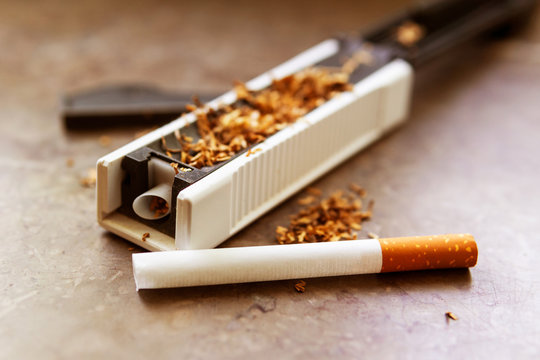 diy tea cigarettes The machine for stuffing cigarettes with tobacco. Empty sighety. Rossypany  tobacco on the table. Homemade cigarette production Stock Photo