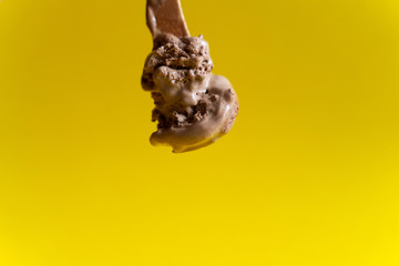 chocolate ice cream on wooden spoon on yellow background
