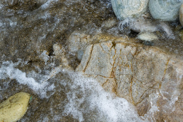 pebble stones on the sea beach, the rolling waves of the sea with foam