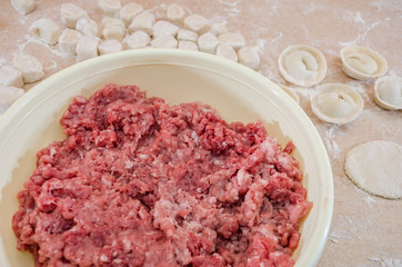 concept of cooking dumplings: dough, minced meat, flour on the kitchen table.
