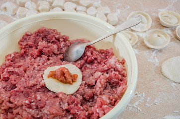 concept of cooking dumplings: dough, minced meat, flour, rolling pin on the kitchen table.
