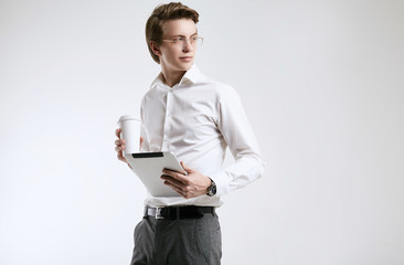 Confident young businessman in shirt with cup of coffee and tablet