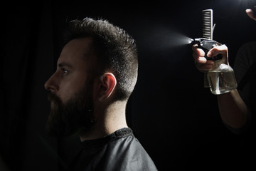 Happy young man getting a haircut. Isolated on dark background