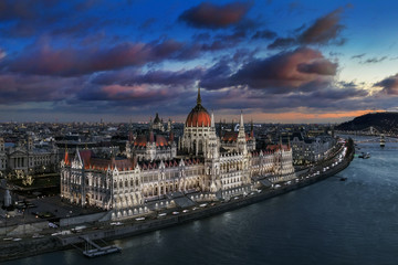 Fototapeta na wymiar Budapest, Hungary - Aerial panoramic view of the beautiful illuminated Parliament of Hungary with Szechenyi Chain Bridge, Statue of Liberty and colurful clouds at background at sunset