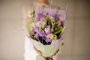 Woman holding a spring bouquet of tender violet, white and pink flowers