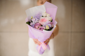 Woman holding a spring bouquet of tender violet and pink roses