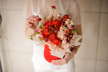 Young woman holding a red velvet box of scarlet and pink flowers