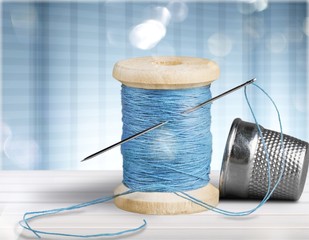Spool with needle and thimble isolated on white