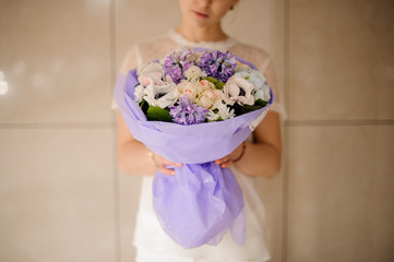 Woman holding a bouquet of tender light color spring flowers