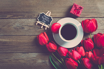 Row of red tulips and cup of black coffee americano on wooden background with space for text, message. Mother's Day, Hello spring, good morning concept. Card. Flat lay. Top view. Rustic style. 