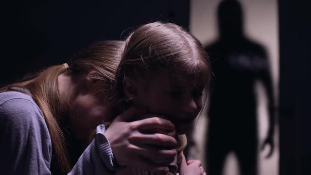 Panic-stricken Woman And Child Watching Scary Monster Silhouette Outside Door