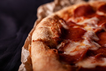 pizza peperoni on black stone background