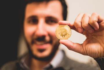 Cryptocurrency golden bitcoin coin. Man holding in hand symbol of crypto currency - electronic virtual money for web banking and international network payment, selective focus, toned