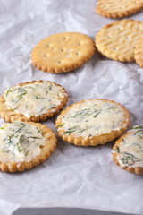 Crackers with smeared garlic butter with dill on white paper