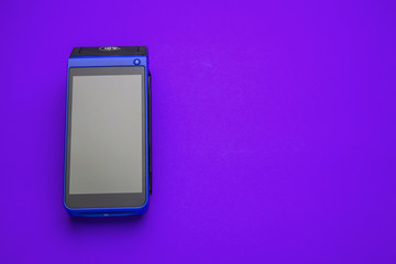 Modern mobile POS terminal with contactless technology. Closeup, blue background, copy space....