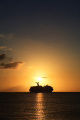 a cruise ship sails along the horizon at sunset
