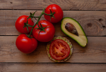 tomato branch with avocado on a wooden table with a buckwheat sandwich