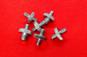 Metal double-sided Nickel-plated screws on a red background - 270270476