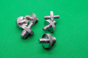 Metal double-sided Nickel-plated screws on a green background - 270270484