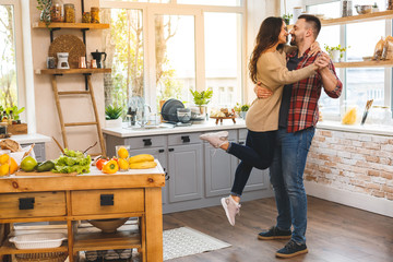 Dancing in kitchen. Young romantic couple celebrating engagement copy space. Cute young couple dancing at home.