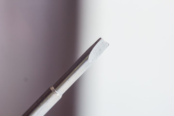 Fototapeta premium head of a metal flat screwdriver close-up on a blurred background. hand tool close up. copy space