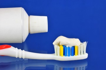 Toothbrush, tube of toothpaste, blue background. Oral hygiene products - toothbrush — a device for brushing teeth and gum massage, used with toothpaste. Dental toothbrushes are diverse in shape.